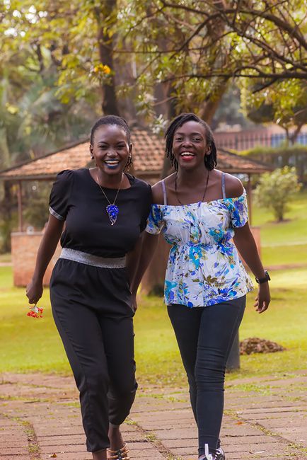 Two friends enjoy a walk in the park, laughing and smiling on a sunny day.
