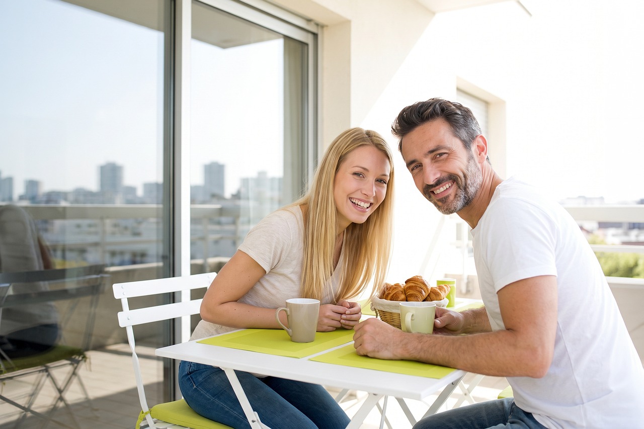 Couple, happy, breakfast, balcony, nature, laughing, city view, celebration, coffee, croissant, urban, summer, lifestyle, relaxation, together, european, blonde hair, outdoor, apartment, day