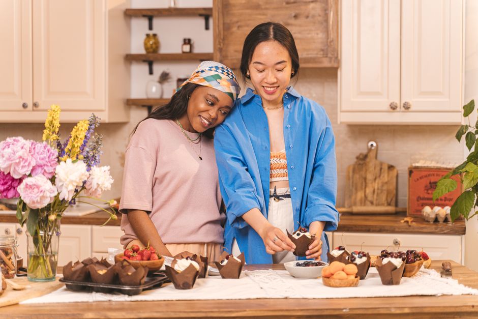 Two friends enjoy baking cupcakes together in a warm, inviting kitchen setting.