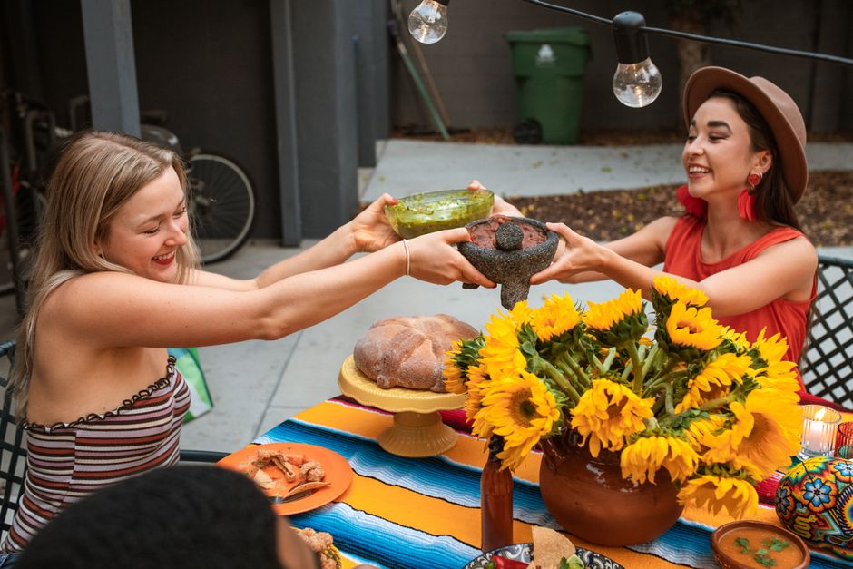 A vibrant outdoor meal with friends sharing food and laughter, surrounded by colorful decor.