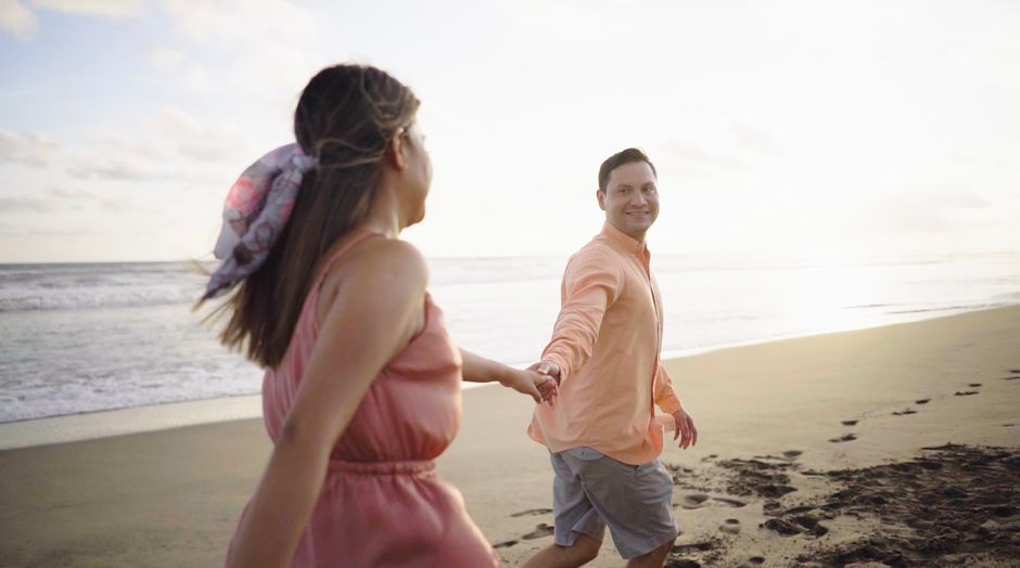 Happy couple walking hand in hand on a serene beach during sunset, capturing love and romance.