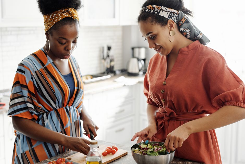 Two women in a modern kitchen preparing a fresh salad together. Vibrant and stylish setting.