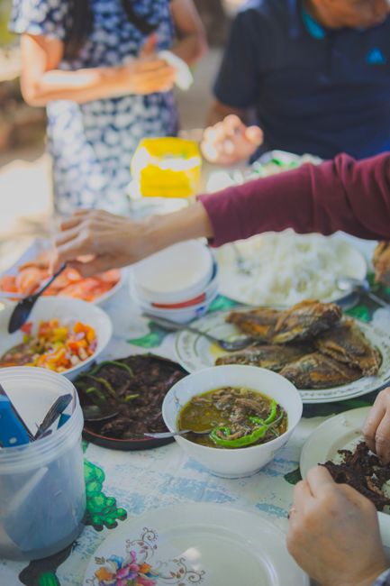 A lively family dinner with diverse homemade dishes on a sunny day outdoors.