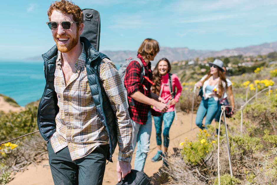 Friends enjoy a sunny hiking day along a coastal trail with stunning ocean views and vibrant nature.