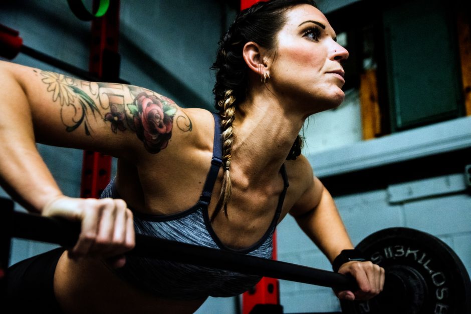 Focused woman lifting weights in a gym, showcasing strength and motivation.