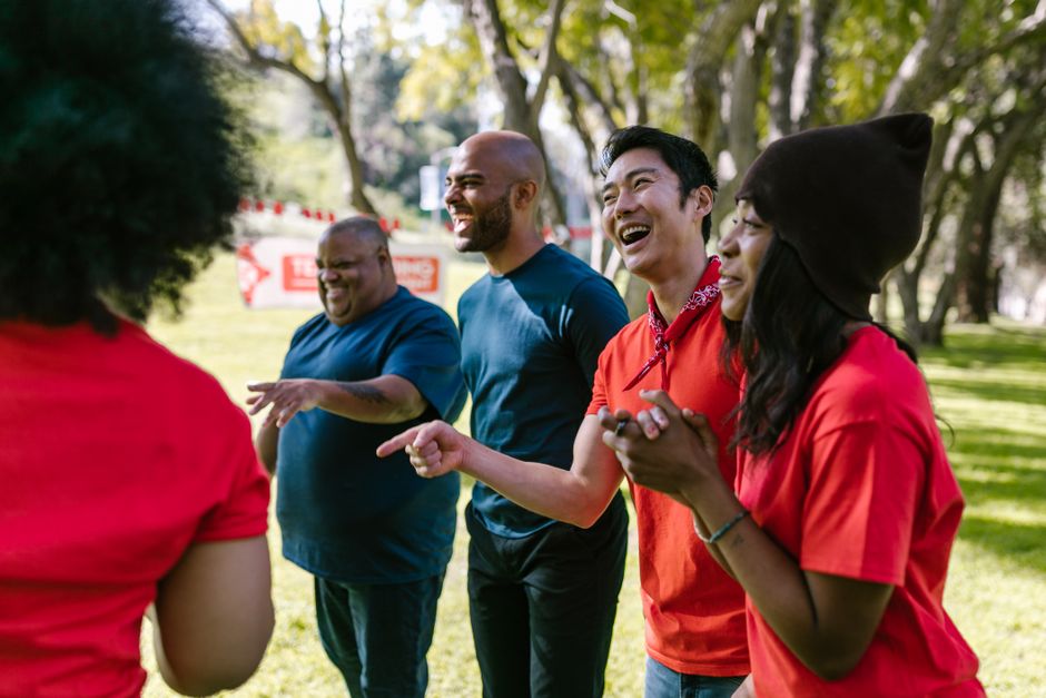 A diverse group of adults enjoying a lively team-building activity in a sunny park.