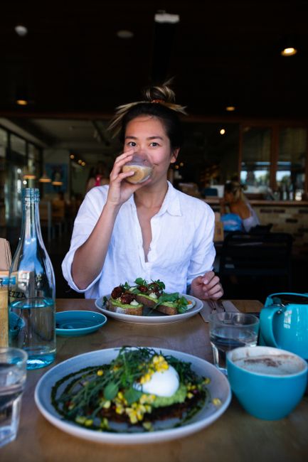 An Asian woman dining on a healthy meal in a trendy urban cafe, enjoying her drink.
