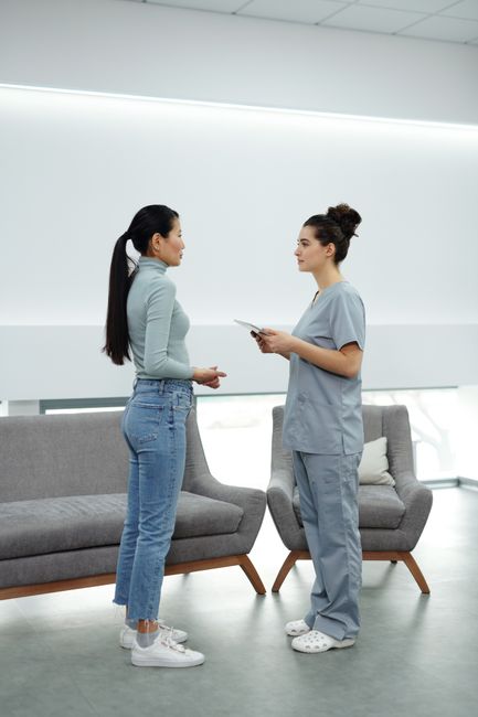 A doctor in scrubs discusses with a patient in modern clinic setting.