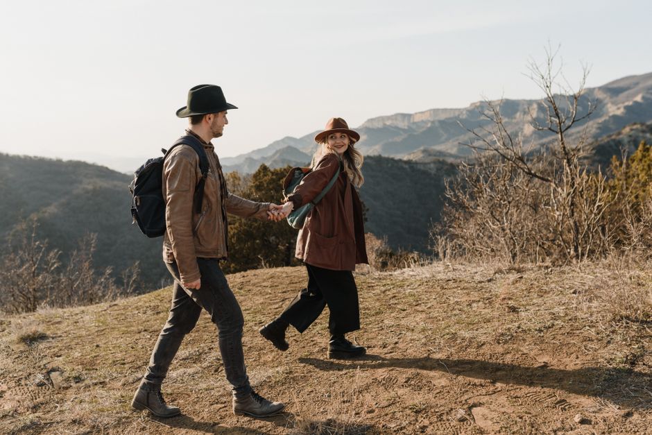 A couple hiking and holding hands, enjoying the fall landscape in the mountains.