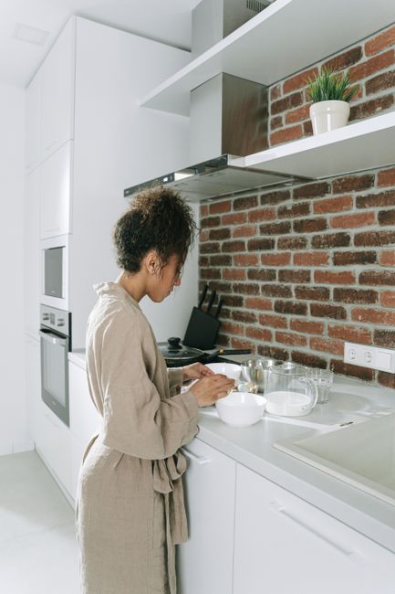 A woman is focused on preparing a meal in a bright, modern kitchen.