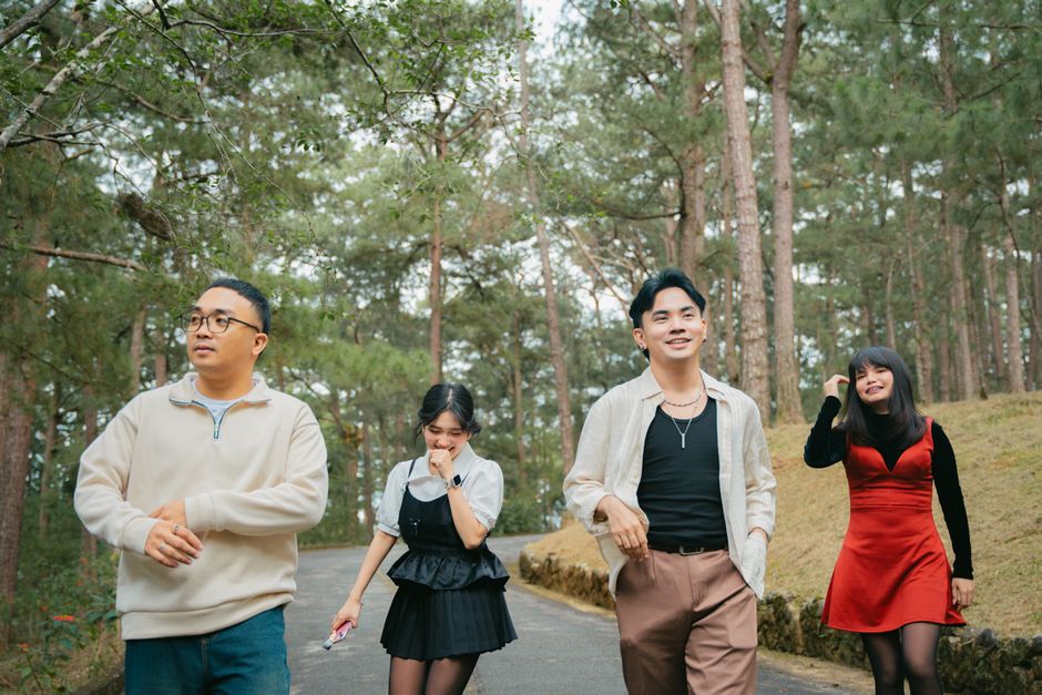 Four friends walking joyfully through a forest trail, enjoying a sunny day outdoors.