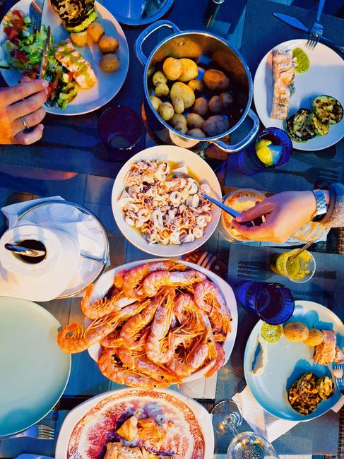Colorful seafood dinner spread with shrimp, potatoes, and salads shared among friends.