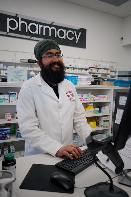 Smiling pharmacist with a turban assisting at the pharmacy counter.