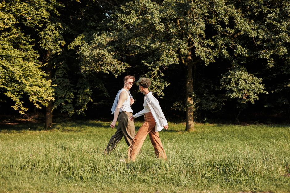 Two young adults enjoying a refreshing walk in a sunny park during summer.