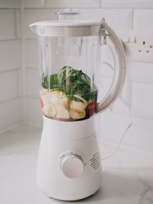 A blender filled with bananas, spinach, ready for a healthy smoothie.