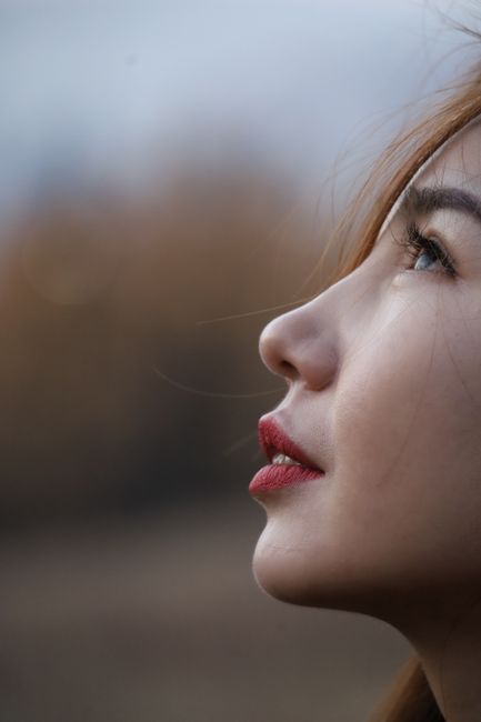 Elegant outdoor profile portrait of a woman gazing upwards, capturing a serene moment.