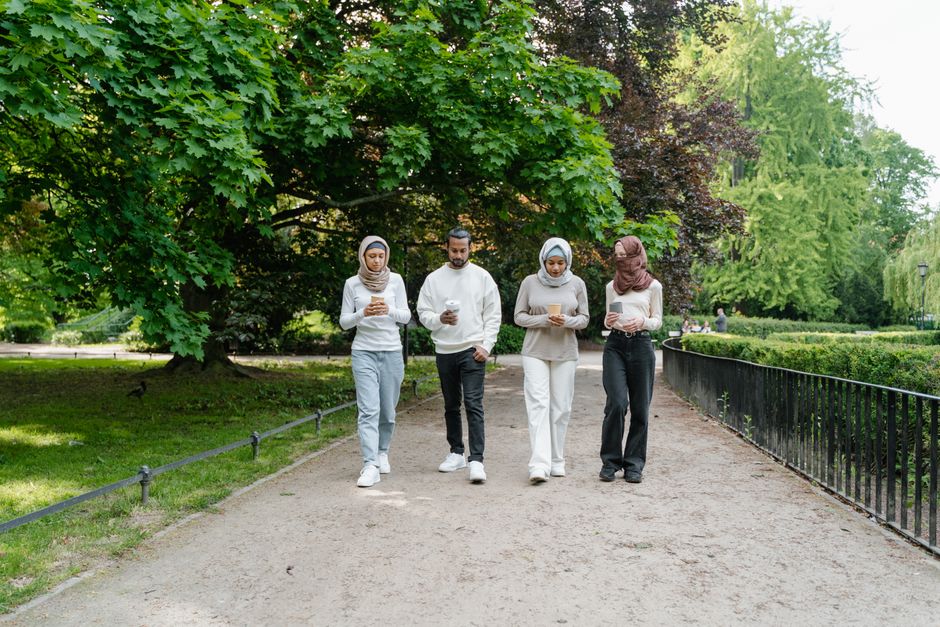 A diverse group of friends walking together in a beautiful green park, enjoying leisure time outdoors.