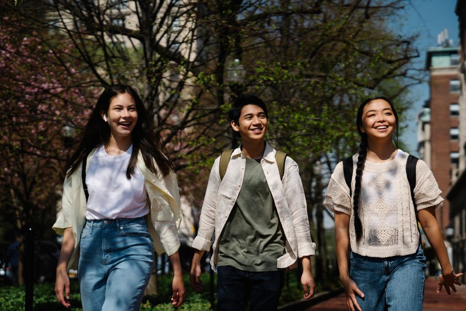Three friends enjoying a sunny day walking together outdoors.