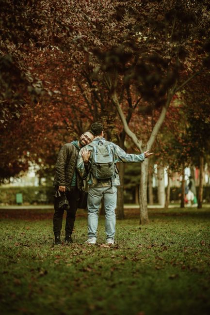 Two friends enjoying a walk in a park during autumn, surrounded by colorful fall foliage.