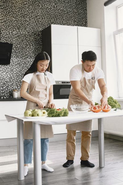 Asian couple preparing healthy meals together in a modern kitchen, highlighting teamwork and healthy living.